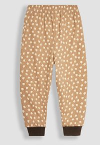 Joggers en coton marron avec une taille élastique, ornés d'un motif blanc de petites formes de feuilles et de poignets de cheville marron foncé.