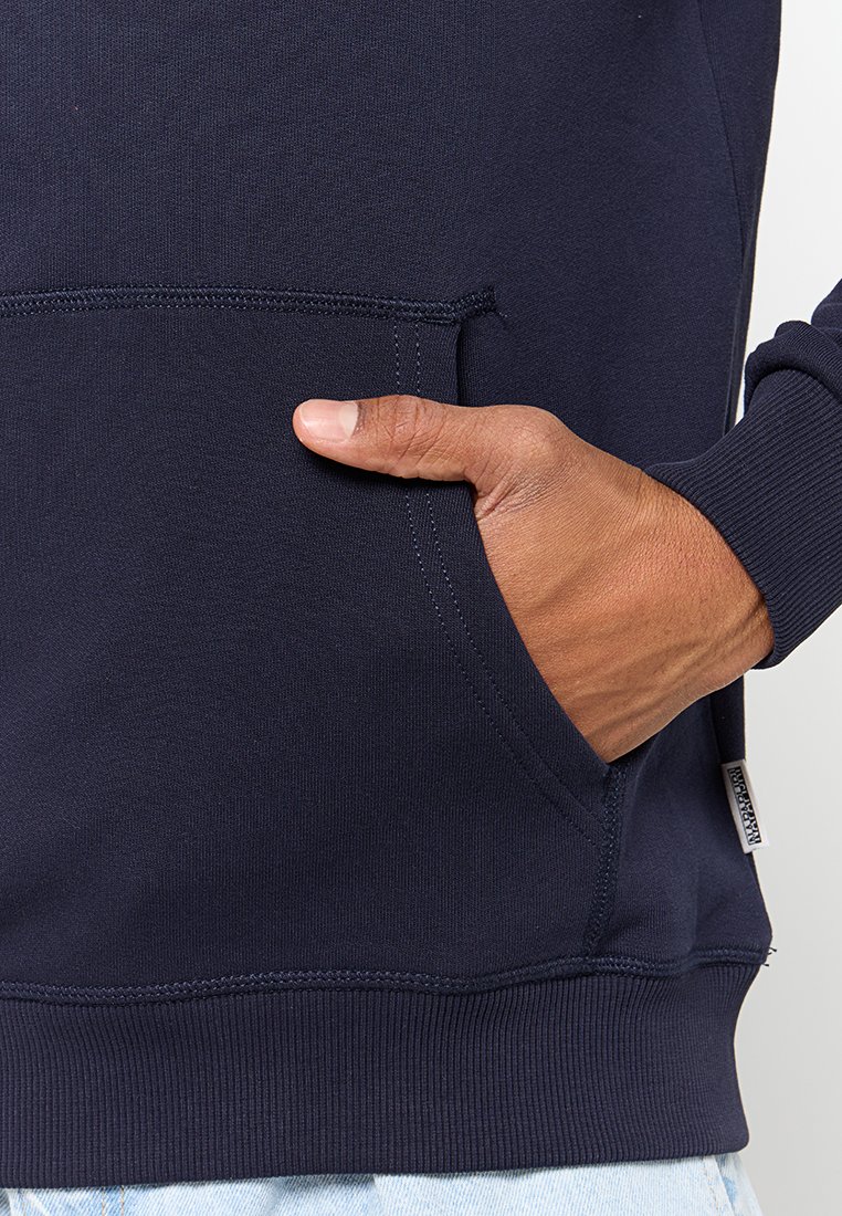Felpa con cappuccio blu navy, dotata di tasca a marsupio, polsini e orlo a coste e texture liscia. Presenta un piccolo etichetta sulla cucitura laterale.