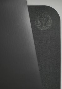 Černá joga podložka s texturovaným povrchem a zaoblenými rohy, s jemným vyraženým logem. Materiál působí odolně a protiskluzově.