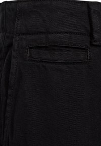 Sorte denimbukser med en baglomme med et diskret stingmønster. Tøjet har en glat tekstur med en let glans.