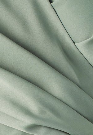 Lichtgroene stof met een gladde, matte textuur, met zachte plooien en draping. Geen zichtbare patronen of hardware-details aanwezig.