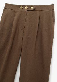 Bruine linnen blend broek met een getailleerde snit, voorzien van een hoge tailleband, drie gouden knopen en zijzakken.