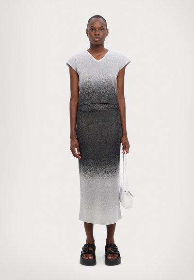 Rochie tricotată ombre gri, cu mâneci scurte, decolteu în V, siluetă ajustată și finisaj texturat. Sandale cu platformă negre, geantă albă cu umăr cu lanț.