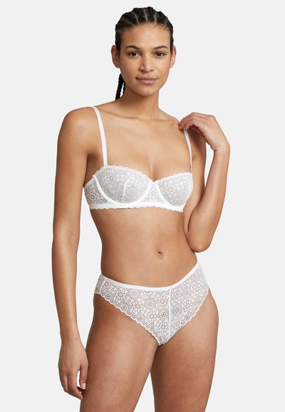 Wit kanten lingerieset met een balconette beha met verstelbare bandjes en bijpassende hoge slip, beiden met bloemenpatronen.