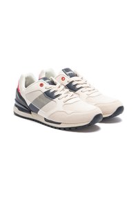 Zapatillas beige con acentos en azul marino y rojo. Materiales de ante y malla, cuello acolchado, cordones planos y una suela de goma texturizada. Logo en la lengüeta.