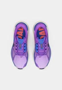 Μωβ αθλητικά παπούτσια με υφή στο επάνω μέρος, αντίθετες μπλε λεπτομέρειες, ένα εμφανές κόκκινο λογότυπο και ανοιχτό γκρι σόλα.