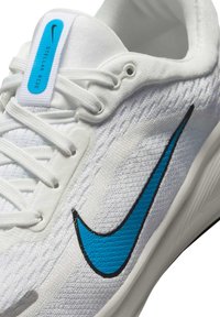 Biele športové topánky s textúrovaným zvrškom a modrým logom Nike Swoosh. Obsahujú svetlé šnúrky, polstrovaný golier a modrý štítok s nápisom "Stellar Ride".