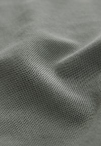 Material gri texturat cu un model fin, asemănător unei rețele. Materialul pare ușor și ușor șifonat, dezvăluind o textură moale.