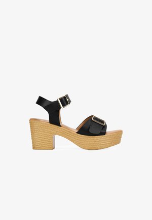 Black platform sandals with a smooth satin finish, wide front strap, ankle strap with a gold buckle, and textured jute-wrapped heel.
