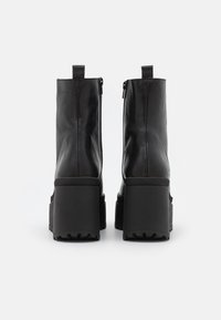 Bottines en cuir noir avec une semelle épaisse en plateau, des zips latéraux et des languettes à l'arrière pour un enfilage facile. Semelle extérieure en caoutchouc texturé.