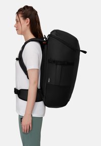 Czarny plecak o smukłym designie. Wykonany z wytrzymałego materiału, z regulowanymi szelkami, uchwytem na górze i wieloma przegródkami.