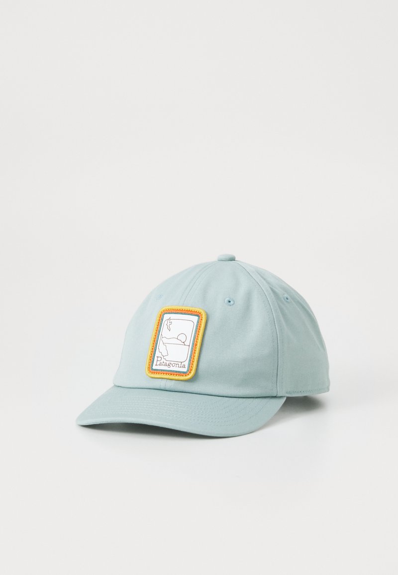 Casquette de baseball bleue claire en tissu, dotée d'un patch rectangulaire blanc avec une bordure jaune et une illustration. Visière incurvée, sangle ajustable.