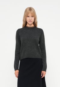 Mørkegrå genser med rund hals og lange ermer; har en blonderkant ved halsen; myk tekstur, litt kortere design.