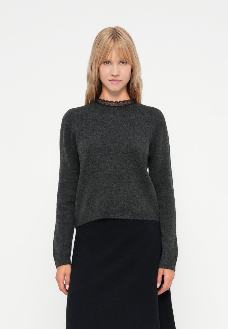 Mørkegrå genser med rund hals og lange ermer; har en blonderkant ved halsen; myk tekstur, litt kortere design.