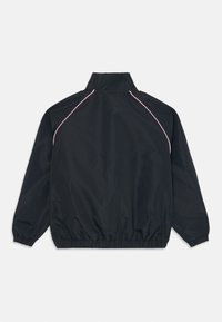 Svart långärmad jacka med hög krage, elastiska cuffs och nederkant, med tunna rosa pipings längs raglanärmsömmarna på baksidan.