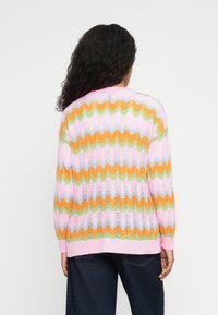 Πλεκτό ζακέτα με ζιγκ-ζαγκ σχέδιο σε ροζ, πορτοκαλί, πράσινο και μπλε, με χαλαρή εφαρμογή και ριμπ μανσέτες. Υφή, ελαφρύ ύφασμα.