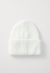 Bonnet en tricot vert clair avec une texture côtelée, doté d'un revers et d'une couture verticale sur le sommet.