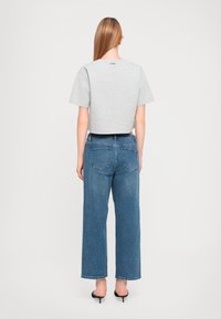 Cropped gray t-shirt with short sleeves paired with high-waisted, wide-leg blue jeans. Black heeled sandals complete the look.