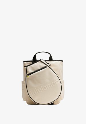 Beiger Stoffrucksack mit abgerundetem Reißverschlussfach vorne, schwarzen Akzenten und geprägtem Schriftzug. Verfügt über zwei Tragegriffe und Seitentaschen.