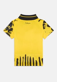 Polo giallo con colletto nero. Presenta motivi astratti neri sulle maniche e sui bordi inferiori. Logo sul retro del colletto.