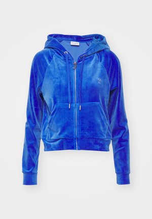 Niebieska aksamitna bluza na zamek z kapturem, przednią kieszenią kangurką, sznurkiem w kapturze i małym haftowanym logo na lewej piersi.