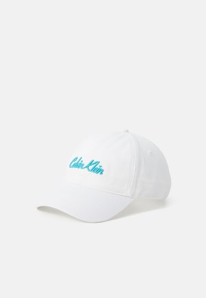 White baseball cap with a curved brim, featuring turquoise embroidered "Calvin Klein" logo on the front. Cotton fabric with smooth texture.