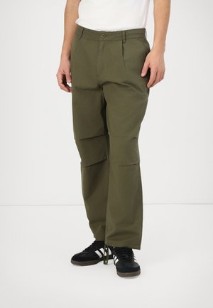 Olive green cargo pants with a relaxed fit, featuring front pleats and side pockets, paired with black athletic shoes.