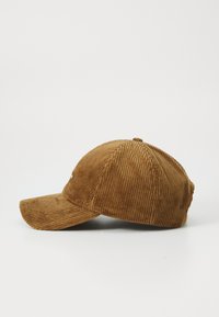 Bruine corduroy baseballpet met een gebogen rand, van de zijkant weergegeven op een witte achtergrond.
