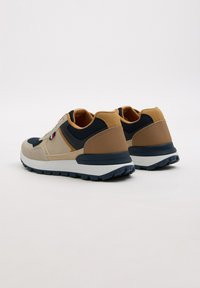 Zapatillas con una combinación de colores beige, marrón claro y marino. Materiales de gamuza y malla, diseño con cordones, suela texturizada y cuello acolchado.