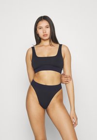 Svart bikini-sett med kvadratisk U-hals topp og høytlivsunderdel. Stoffet er glatt med en kontrastfarge på midjebåndet.