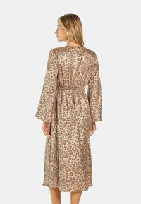 Midikleid mit Leopardenmuster aus einem glatten Stoff. Hat lange Glockenärmel, einen elastischen Bund und einen lässigen Schnitt.