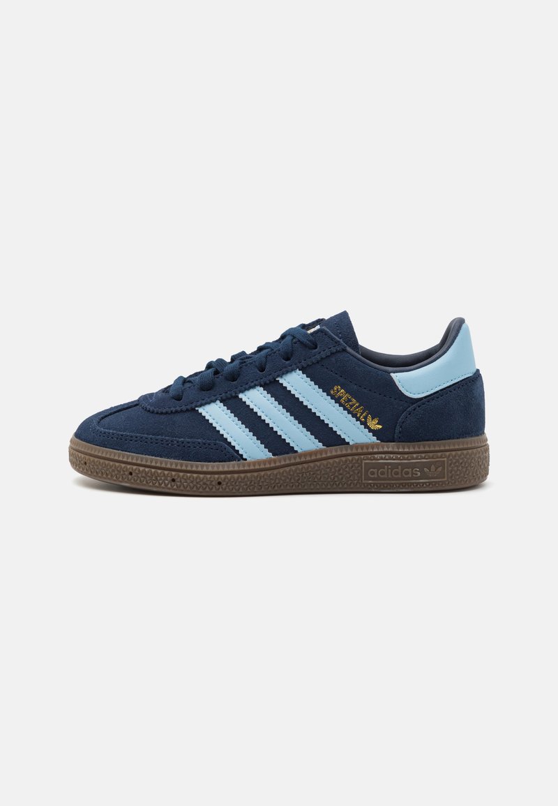Navy suede sports shoes featuring three light blue stripes, gold branding, and a textured brown rubber sole.
