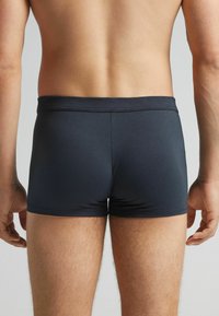 Tmavě modré pánské boxerky s hladkým povrchem, elastickým pasem a přiléhavým střihem, které mají střední výšku a minimální švy.