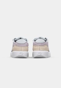 Sneakerji, ki združujejo svetlo sivo, sivkasto in peščeno nubuk usnje. Imajo bel gumijast podplat z teksturiranimi detajli in vidno blagovno znamko.