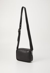 Borsa a tracolla in pelle nera con forma rettangolare, tracolla regolabile, accessori in argento e una texture liscia. Chiusura con zip nella parte superiore.