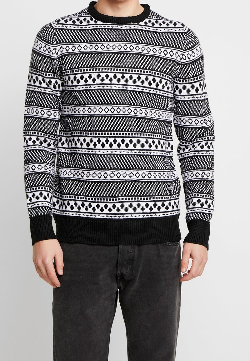 Czarnobiały sweter z wzorem w geometryczne kształty, z okrągłym dekoltem, ściągaczami na mankietach i u dołu. Wykonany z dzianiny.