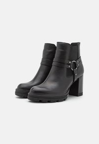 Botas de tobillo de cuero negro con un acabado texturizado, tacón grueso y dos correas horizontales con un acento metálico. Suela gruesa y resistente.