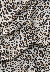 Leopardprint stof med en cremet baggrund og sorte og beige pletter i forskellige størrelser og former, der fremhæver en glat og silkeagtig tekstur.