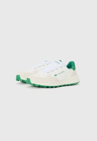Lacoste sneakers met een witte stoffen bovenkant, groene accenten en een rubberen zool met textuur. Opvallende kenmerken zijn de witte veters en het logo.
