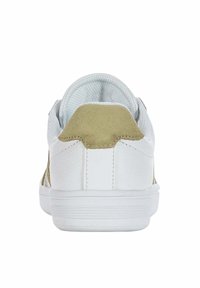 White athletic shoe with a textured surface, padded collar, and a contrasting beige suede heel accent. Solid rubber sole.