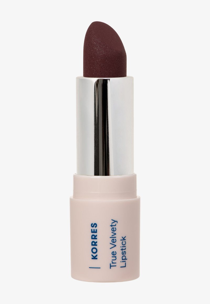 Rouge à lèvres True Velvety de Korres en couleur prune foncée, présenté dans un étui en forme de tube rose et argent. Texture lisse avec une pointe arrondie pour une application précise.