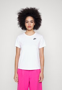 T-shirt en coton blanc avec un logo Nike noir sur la poitrine gauche, col rond, manches courtes et coupe décontractée.