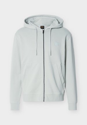 Hellgrauer Reißverschluss-Hoodie mit Kordelzugkapuze, Fronttaschen und kleinem quadratischem Logo auf der linken Brust, dargestellt vor weißem Hintergrund.