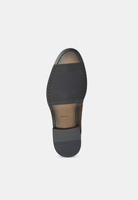 Talpă de piele cu grip din cauciuc texturat. Prezintă un vârf rotund, un toc înclinat de contrast și cusături vizibile de-a lungul marginii.