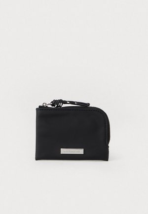 Portafoglio zip rettangolare nero con tirante intrecciato e piastra logo in metallo argento sul fronte, sfondo bianco.