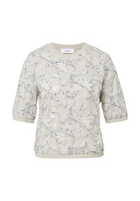 Haut brodé en crème avec un motif floral en bleu clair et blanc, présentant des manches courtes et un col rond avec une bordure décorative.