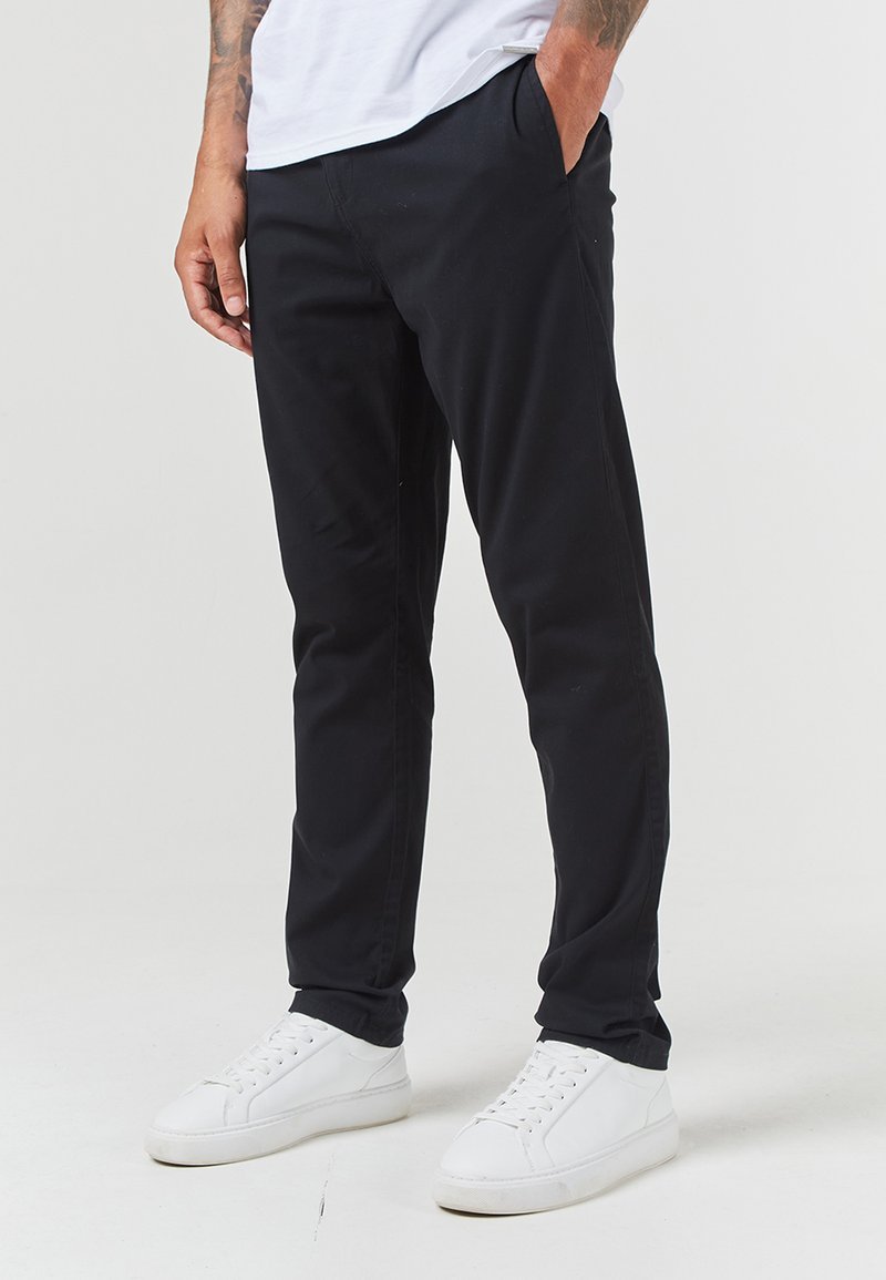 Czarne chinosy o slim fit, wykonane z gładkiego materiału. Posiadają boczne kieszenie oraz minimalistyczny design. W połączeniu z białymi sneakersami.