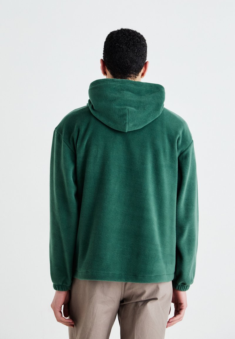 Grüne Kapuzenjacke aus weichem Stoff, mit bequemer Passform, elastischen Bündchen und glatter Textur. Keine sichtbaren Muster oder Grafiken.