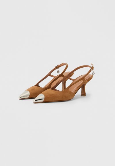 Chaussures slingback en daim marron avec bout pointu et embout argenté métallique. Elles comportent un talon fin et un charm décoratif près de la bride.