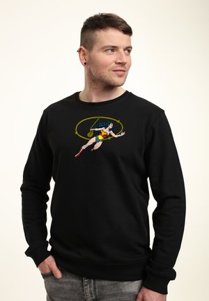Sweatshirt noir avec un graphique d'un super-héros en mouvement, doté d'accents colorés. Fabriqué en tissu doux avec un col rond et des poignets côtelés.